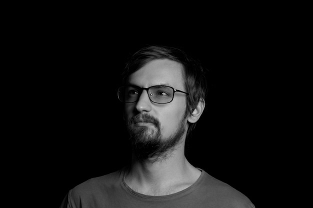 Portrait d'un gars avec une barbe à lunettes sur fond noir