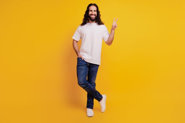 Portrait d'un gars joyeux et positif montre la poche à main du signe v sur fond jaune