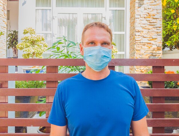 Portrait d'un gars avec un masque médical Dehors marchant dans le jardin près de la maison d'été moderne Il veut respirer attendre la fin de la quarantaine Isolement Covid19 et recommencer une vie normale