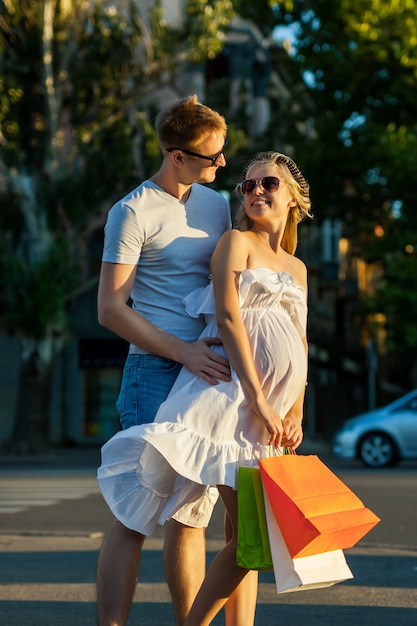 Portrait de gens heureux avec mari et femme enceinte shopping dans la rue de la ville