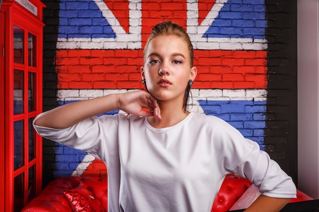 Portrait glamour de mode d'un modèle de fille avec un pull blanc sur fond de mur avec un drapeau britannique