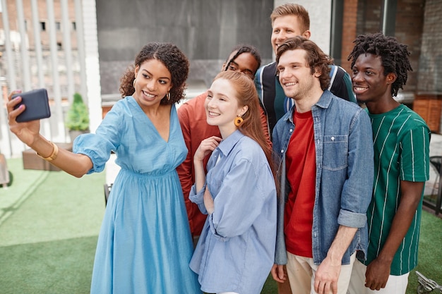 Portrait en grand angle d'un groupe diversifié d'amis prenant un selfie lors d'une fête en plein air
