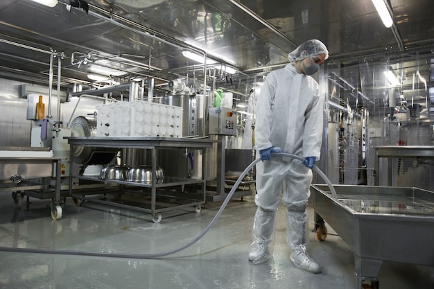 Portrait grand angle sur toute la longueur d'une travailleuse lavant l'équipement dans une usine de production d'aliments propres, espace pour copie