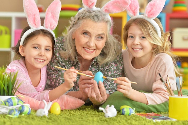 Le portrait d'une grand-mère et de deux petites-filles peignent des oeufs de Pâques