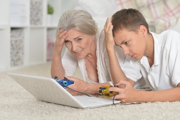 Portrait de grand-mère et petit-fils jouant à un jeu informatique avec un ordinateur portable