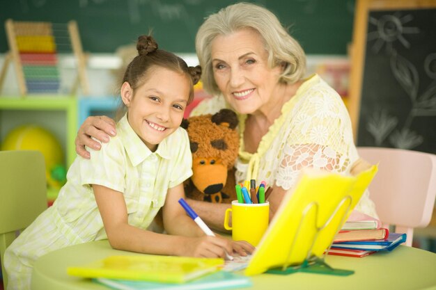 Portrait de grand-mère avec petite fille faisant ses devoirs