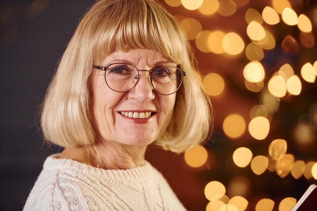 Portrait de grand-mère qui se tient dans la chambre décorée du nouvel an.