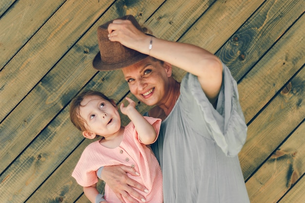 portrait grand-mère et sa petite-fille dans des vêtements de style rural sur fond de bois