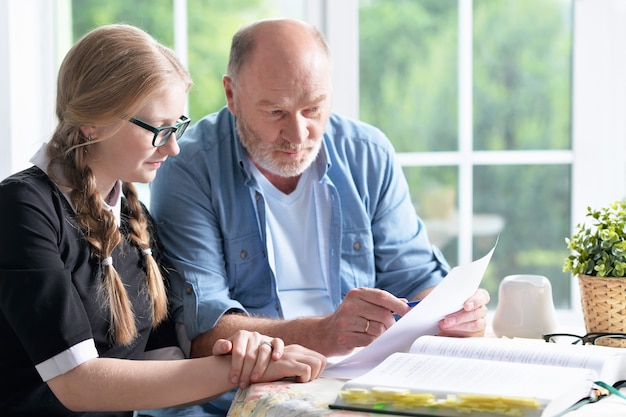 Portrait de grand-père heureux et petite-fille faisant leurs devoirs