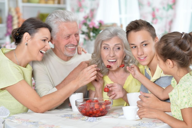 Portrait d'une grande famille heureuse mangeant des fraises fraîches à la cuisine