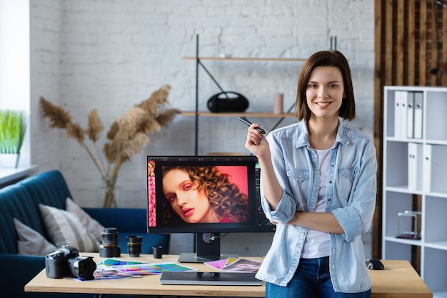 Portrait de graphiste travaillant au bureau avec ordinateur portable, moniteur, tablette graphique et palette de couleurs. Retouche d'images dans un programme spécial. Lieu de travail de retoucheur en studio photo. Agence de création.