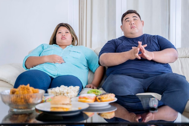 Portrait de gros couple devant la télé avec ennui
