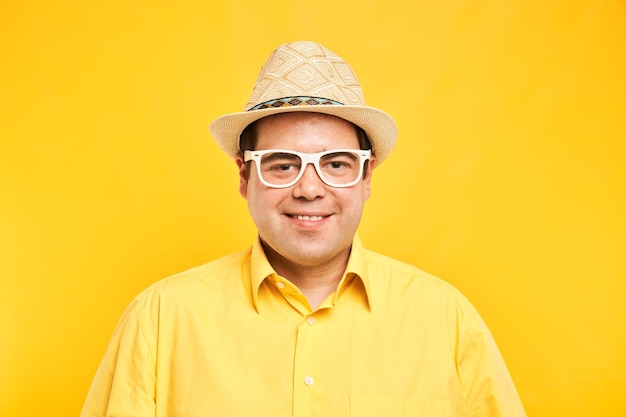 Portrait d'un gros homme positif au chapeau souriant gentiment isolé sur fond de studio jaune concept de vacances de voyage