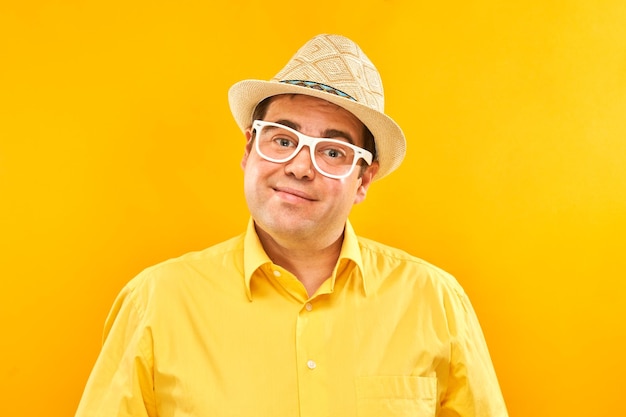 Portrait d'un gros homme positif au chapeau souriant gentiment isolé sur fond de studio jaune concept de vacances de voyage