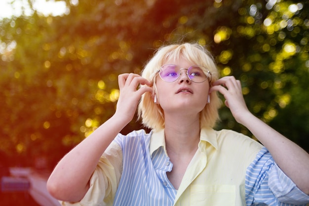 Portrait en gros plan d'une adolescente élégante en plein air dans un casque sans fil Lumière du soleil sur fond