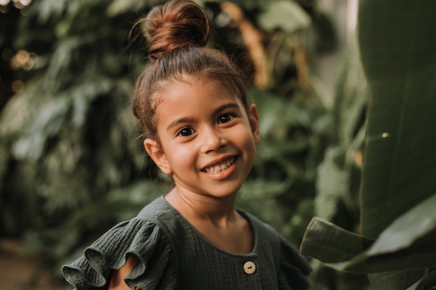 Portrait en gros plan d'un beau bébé basané à la peau parfaite entouré de feuilles tropicales