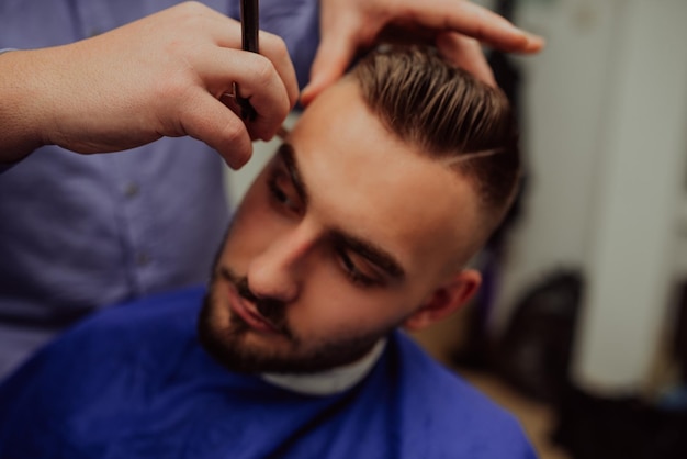 Portrait en gros plan d'un beau jeune homme se rasant la barbe avec un rasoir droit