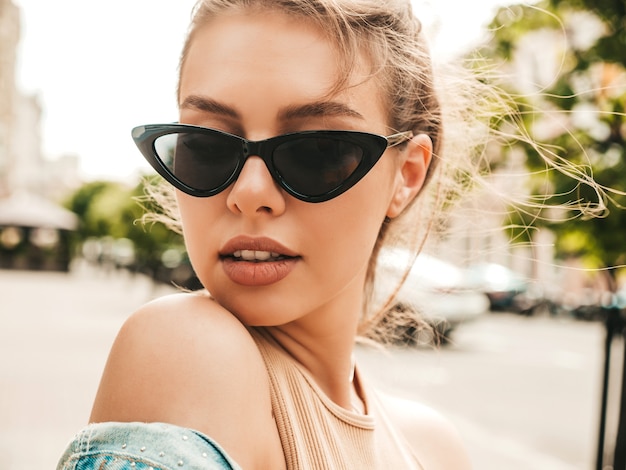 Portrait en gros plan d'un beau modèle souriant vêtu d'une veste en jean d'été hipster