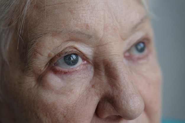 Portrait en gros plan d'une belle femme âgée souriante et debout près d'un mur aux yeux gris