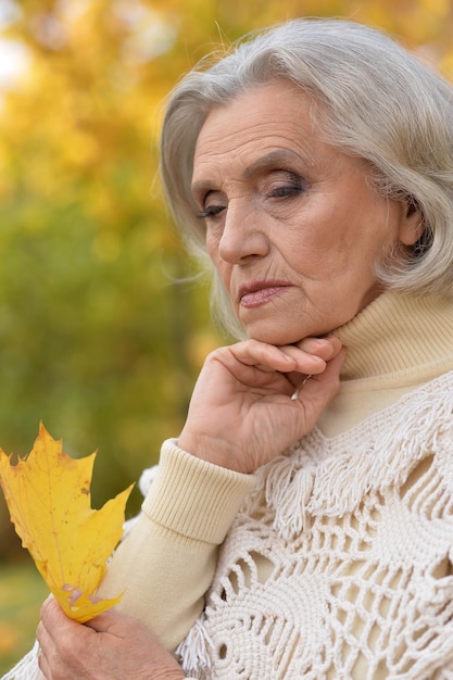 Portrait en gros plan d'une belle femme âgée triste sur fond d'automne flou