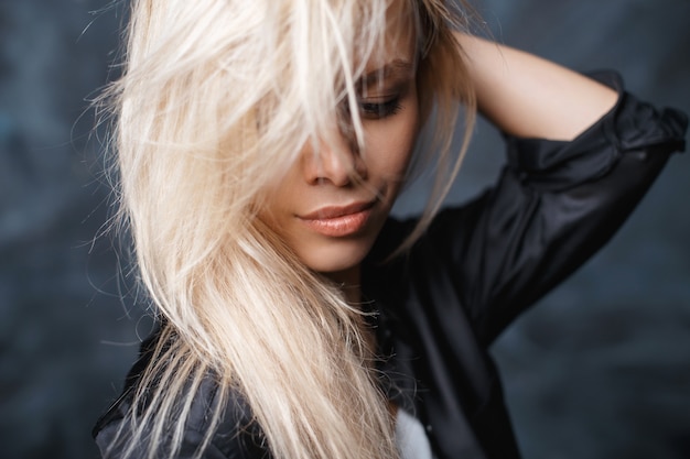 Portrait de gros plan d'une belle femme aux cheveux blonds ébouriffés et de belles lèvres dans une chemise noire élégante