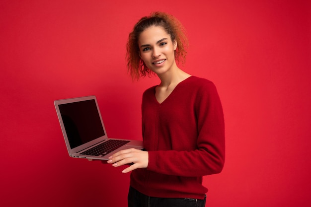 Portrait de gros plan de belle femme demandant et surpris tenant un ordinateur portable