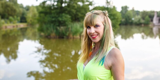 Portrait en gros plan d'une belle femme en robe vert clair avec un maquillage arc-en-ciel lumineux en vue panoramique sur fond vert