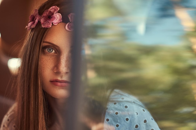 Portrait en gros plan d'une belle femme vêtue d'une robe blanche et d'une couronne blanche sur la tête, assise dans la voiture sur le siège arrière.