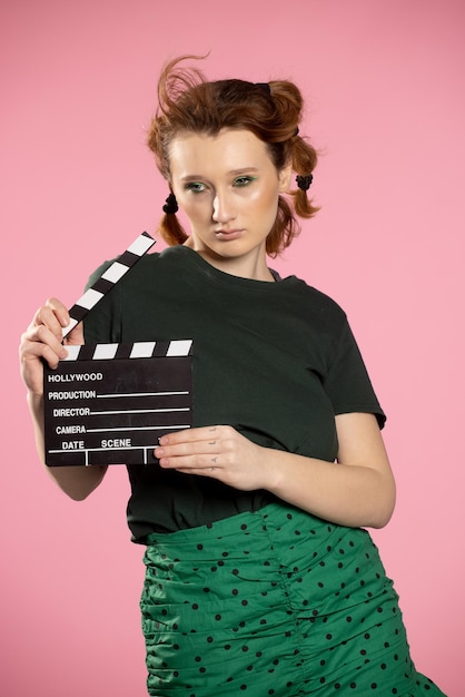 Portrait en gros plan d'une belle fille aux cheveux rouges tenant un battant de film adolescente tenant un classique