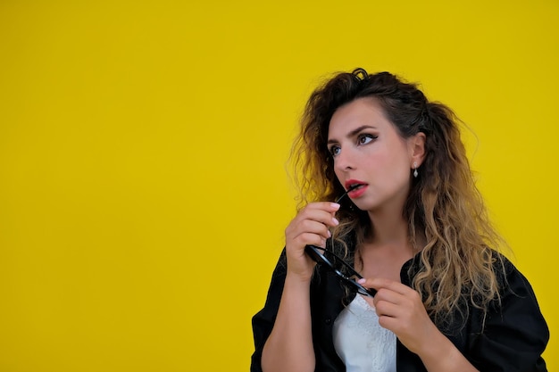 Portrait en gros plan d'une belle fille sur fond jaune femme montre des émotions humaines réfléchies