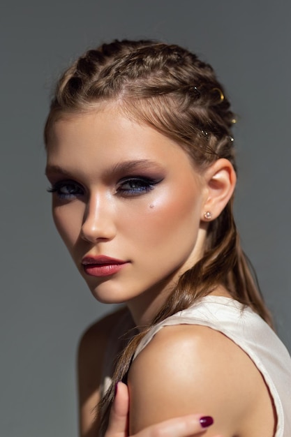 Photo portrait en gros plan d'une belle fille avec maquillage et coiffure sur fond proche. lumière forte