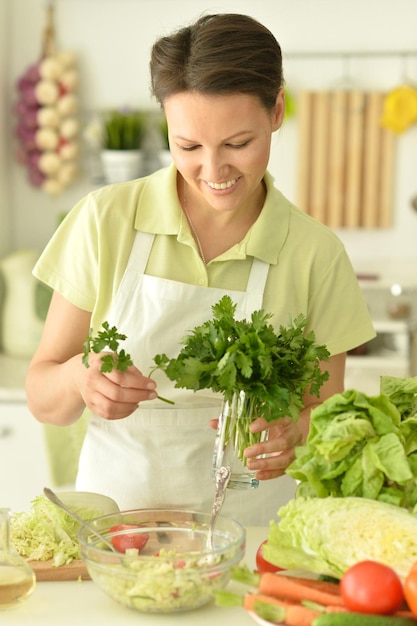 Portrait en gros plan d'une belle jeune femme faisant de la salade dans la cuisine