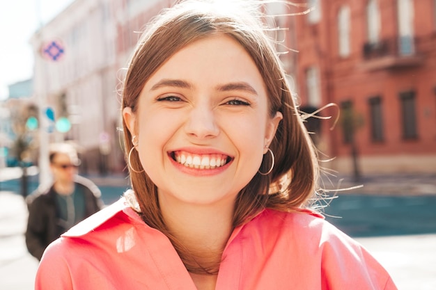 Portrait en gros plan d'une belle jeune femme hipster souriante dans des vêtements d'été à la mode. Sexy femme insouciante posant sur le fond de la rue au coucher du soleil. Modèle positif à l'extérieur