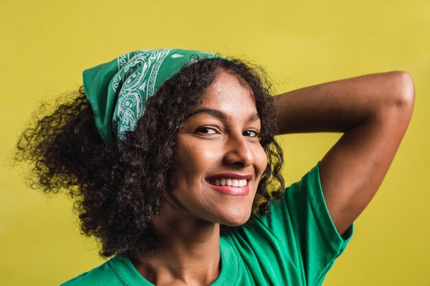 Portrait en gros plan d'une belle jeune femme noire souriante sur fond jaune.