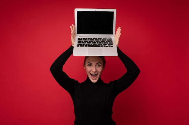 Portrait En Gros Plan D'une Belle Jeune Femme Souriante Et Heureuse Avec Des Cheveux Bruns Réunis Tenant Un Ordinateur