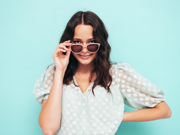 Portrait en gros plan d'une belle jeune femme souriante en robe d'été à la mode Sexy femme insouciante posant près d'un mur bleu en studio Modèle positif s'amusant à l'intérieur