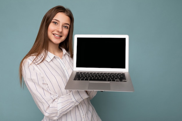 Portrait en gros plan de la belle jeune femme tenant un ordinateur netbook regardant la caméra