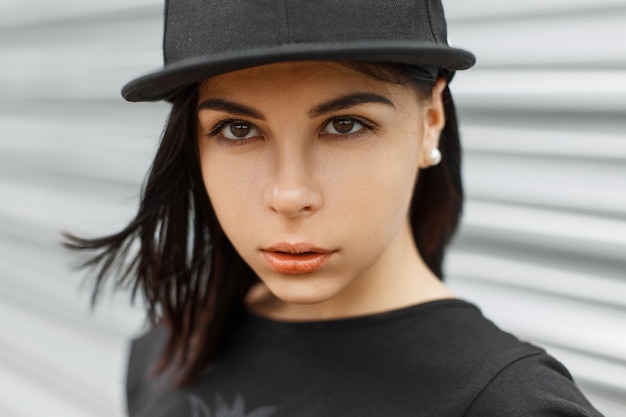 Portrait en gros plan d'une belle jeune fille dans une casquette de baseball noire.