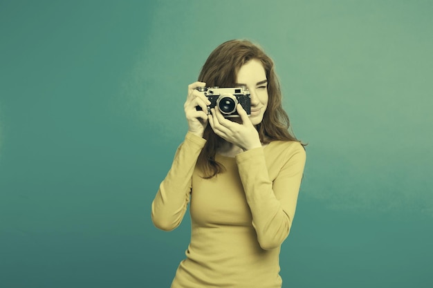 Portrait en gros plan d'une belle jeune fille gingembre attrayante heureuse souriante avec un appareil photo vintage et prête