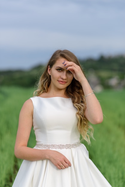 Portrait de gros plan d'une belle mariée. Femme posant dans un champ de blé vert.