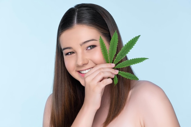 Portrait en gros plan d'une charmante fille dodue à la peau fraîche tenant une feuille de cannabis