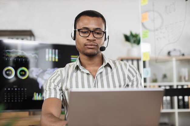 Portrait en gros plan d'un chef de bureau africain confiant en chemise blanche écrivant un rapport financier