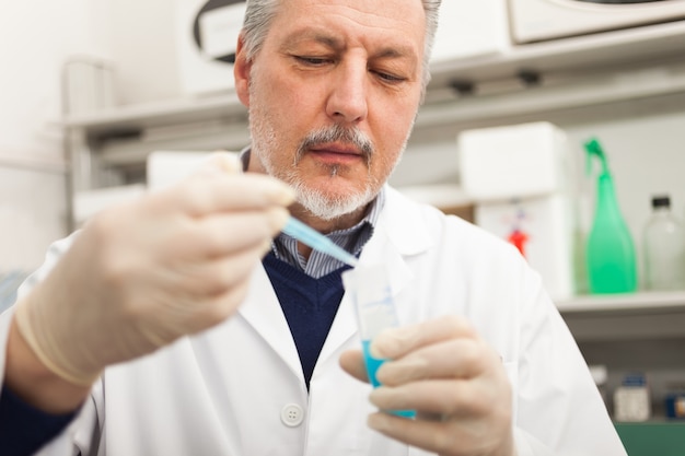 Portrait de gros plan d&#39;un chercheur mâle tenant un flacon de liquide bleu dans le laboratoire