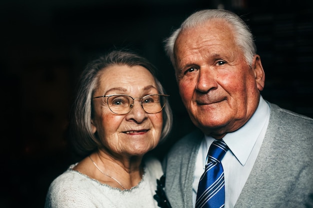 Portrait en gros plan d'un couple d'aînés souriant dans une chambre noire