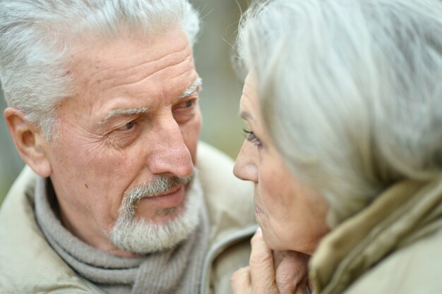 Portrait en gros plan d'un couple de personnes âgées souriant dans des vêtements chauds se regardant à l'extérieur