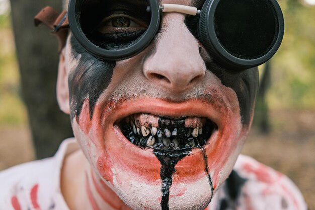 Photo portrait en gros plan du visage d'un zombie avec des traces de sang et de liquide noir coulant de la bouche