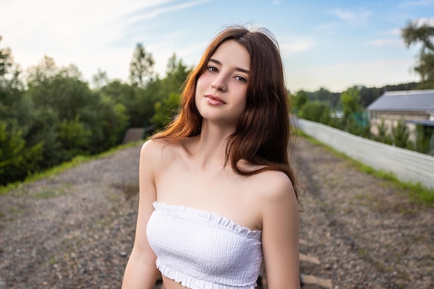 Portrait en gros plan extérieur d'une belle jeune femme en haut posant sur fond de parc