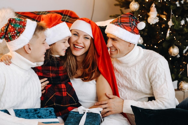 Portrait en gros plan d'une famille heureuse assise sur un canapé près d'un arbre de Noël célébrant des vacances.