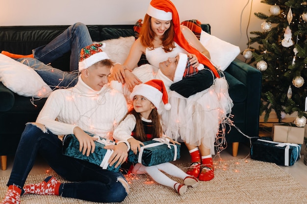 Portrait en gros plan d'une famille heureuse assise sur un canapé près d'un arbre de Noël célébrant des vacances.