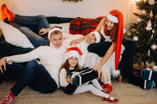 Portrait en gros plan d'une famille heureuse assise sur un canapé près d'un arbre de Noël célébrant des vacances.